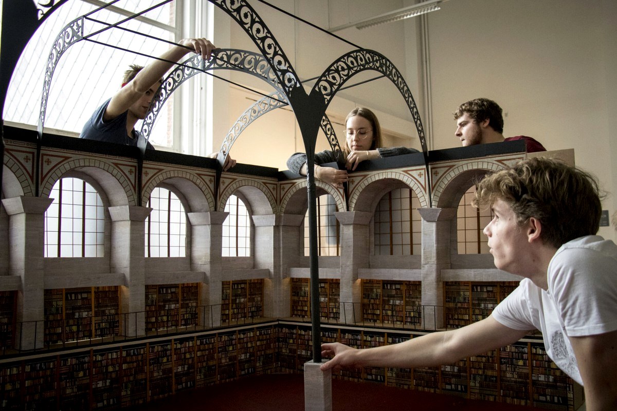 Readers looking across the upper level of a large historic library hall.