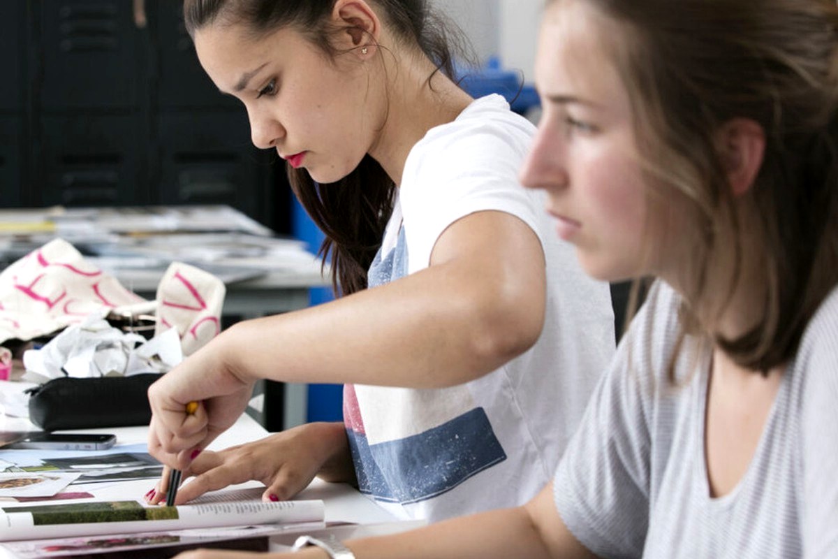 Two people concentrating on a hands-on creative project at a table.